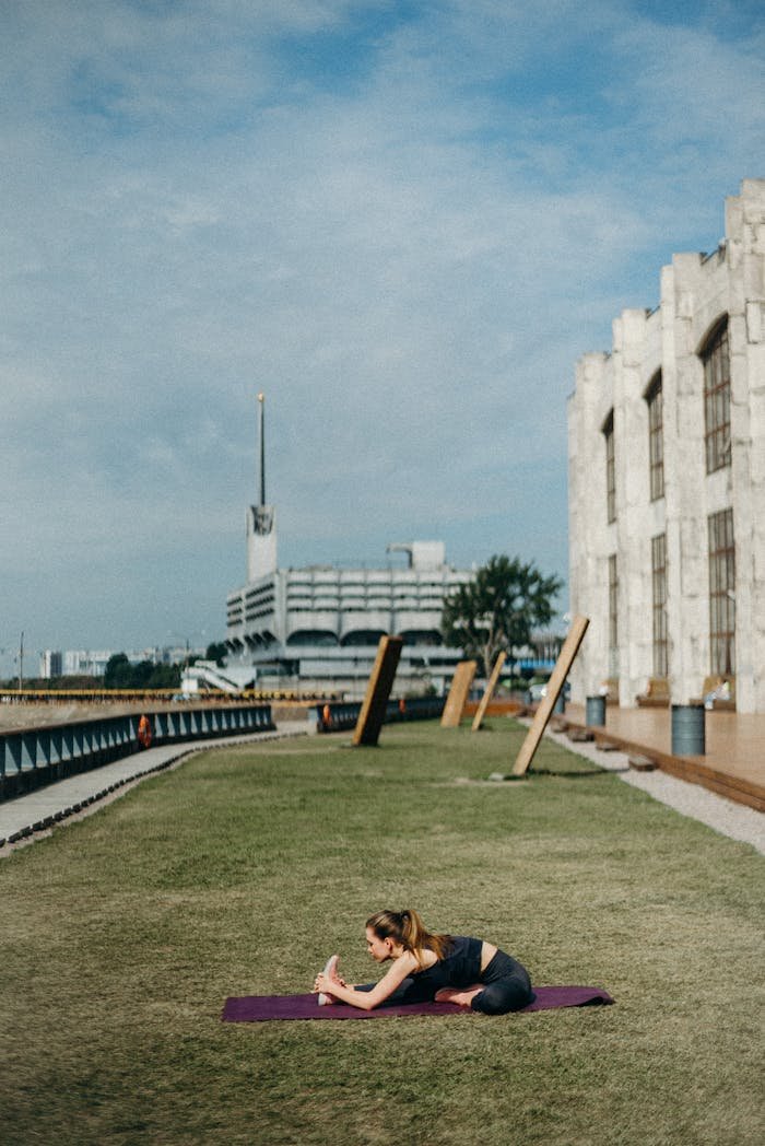 A woman performing yoga stretches on a mat in an urban park setting, promoting fitness and relaxation.